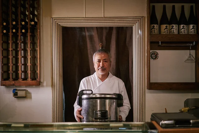 Chef Ikko Kobayashi outside his restaurant beside a chalkboard